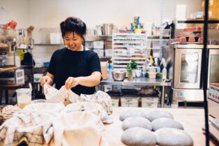 A portrait of Annabelle Choi, 2020 artist in residence making bread at a commercial kitchen.