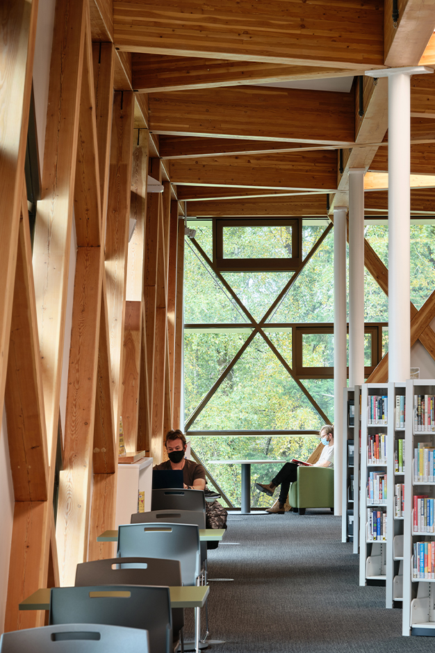 Clayton Community Centre library, showcasing the geometric wood pattern on the walls and ceilings, as well as a view of trees outside.