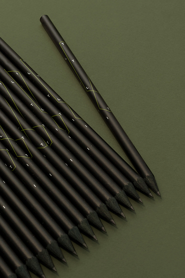 A line up of black cored pencils branded with the TILT logo and a thin green line enclosing the letters.