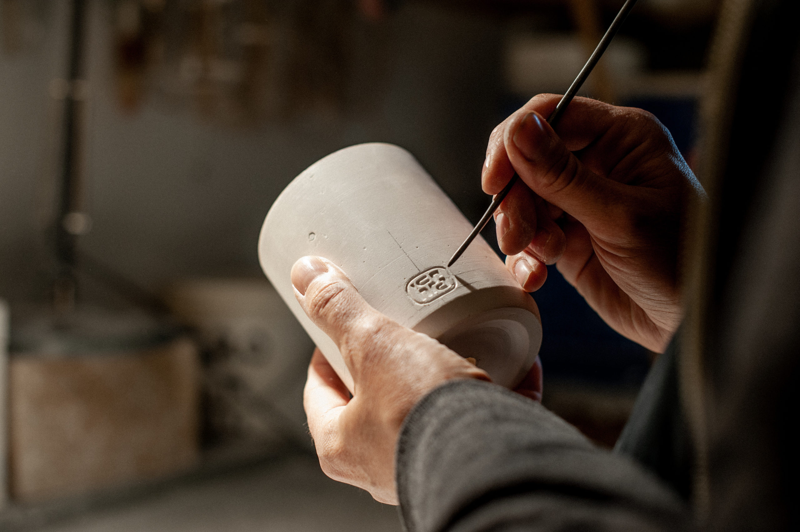 Ruddell Hackney in his home studio hand carving the new rounded HCMA logo into a slipcast mug to soon be used for a mold.