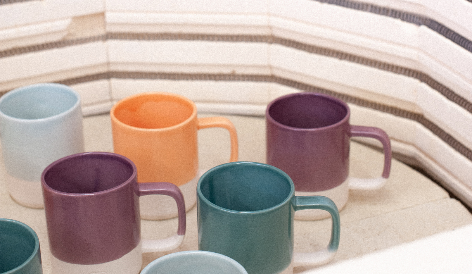 A series of colourfully dipped mugs fresh out of the kiln.