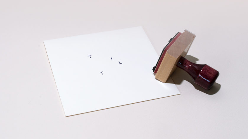A plain, square envelope is stamped with the Tilt logo. Beside it, rests the Tilt stamp on its side.