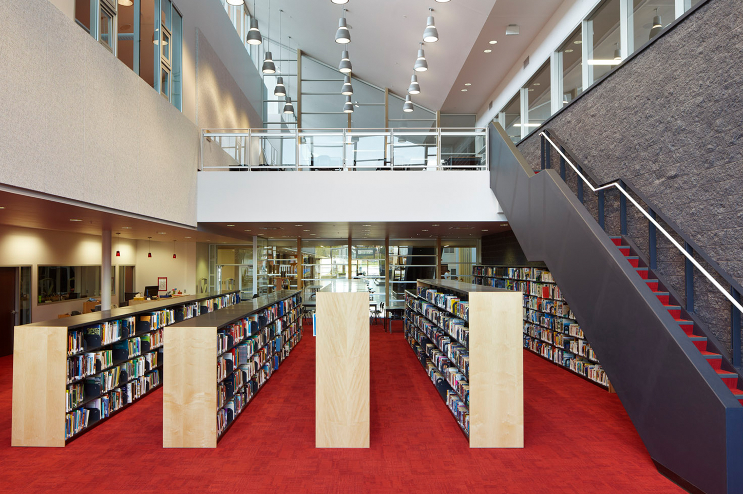 Library with high ceilings and a staircase leading to a balcony