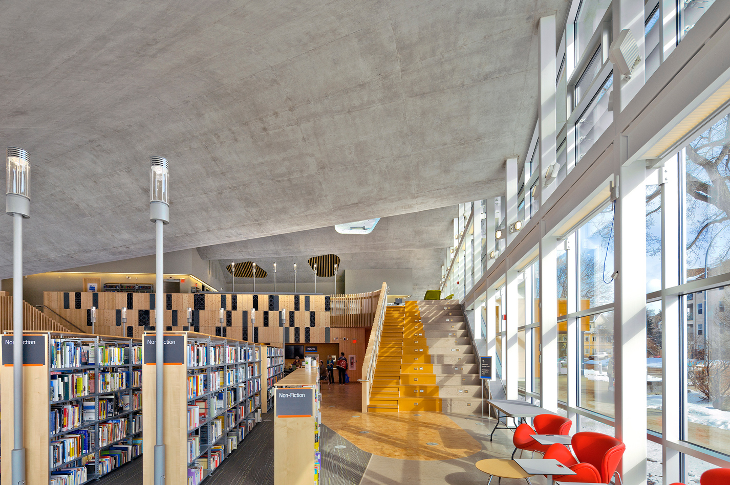 Interior view of library shelves, a staircase and floor-to-ceiling walls