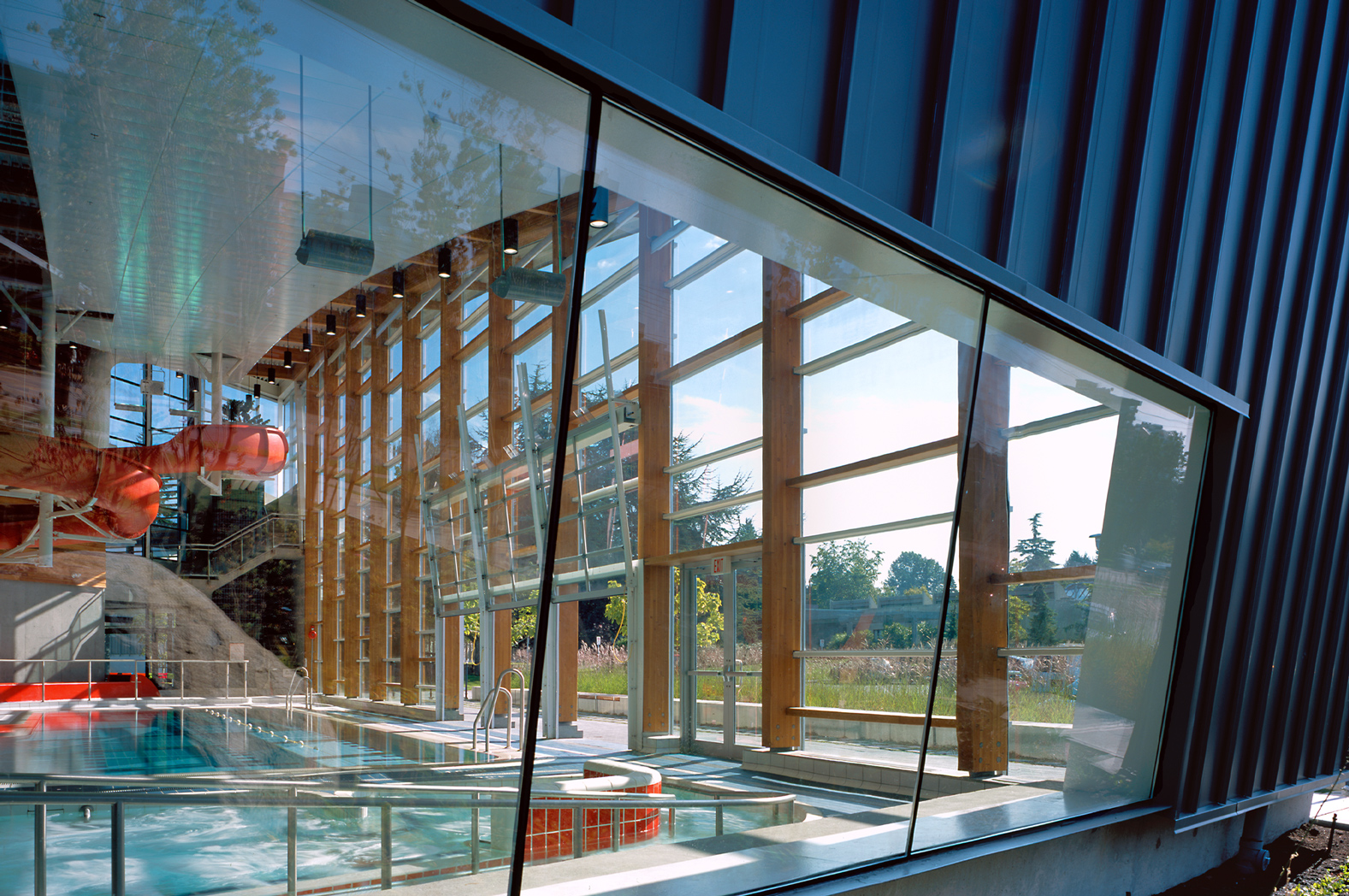 Looking through an outdoor window into the indoor pool, showcasing the large red slide and space that the windows create.