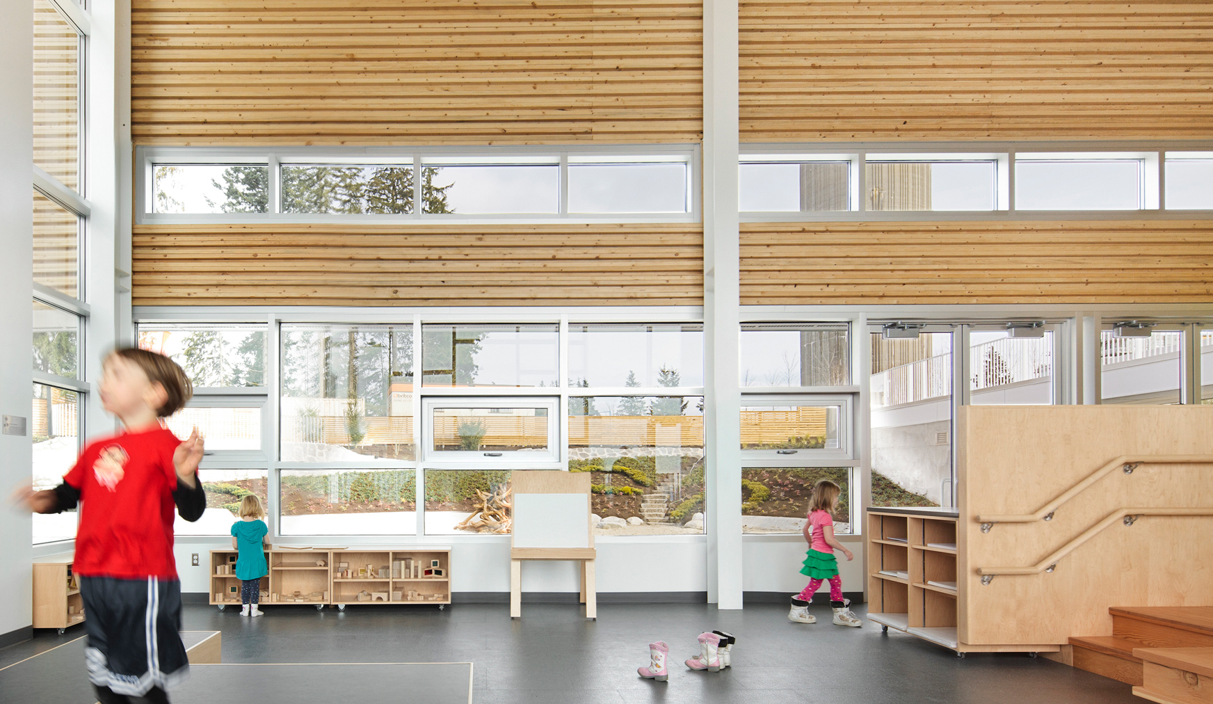 A light wooden interior with lots of windows and children playing.