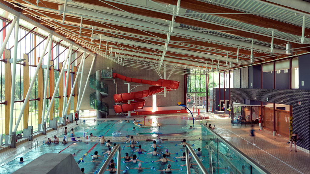 An indoor pool with large windows and a big, red slide.