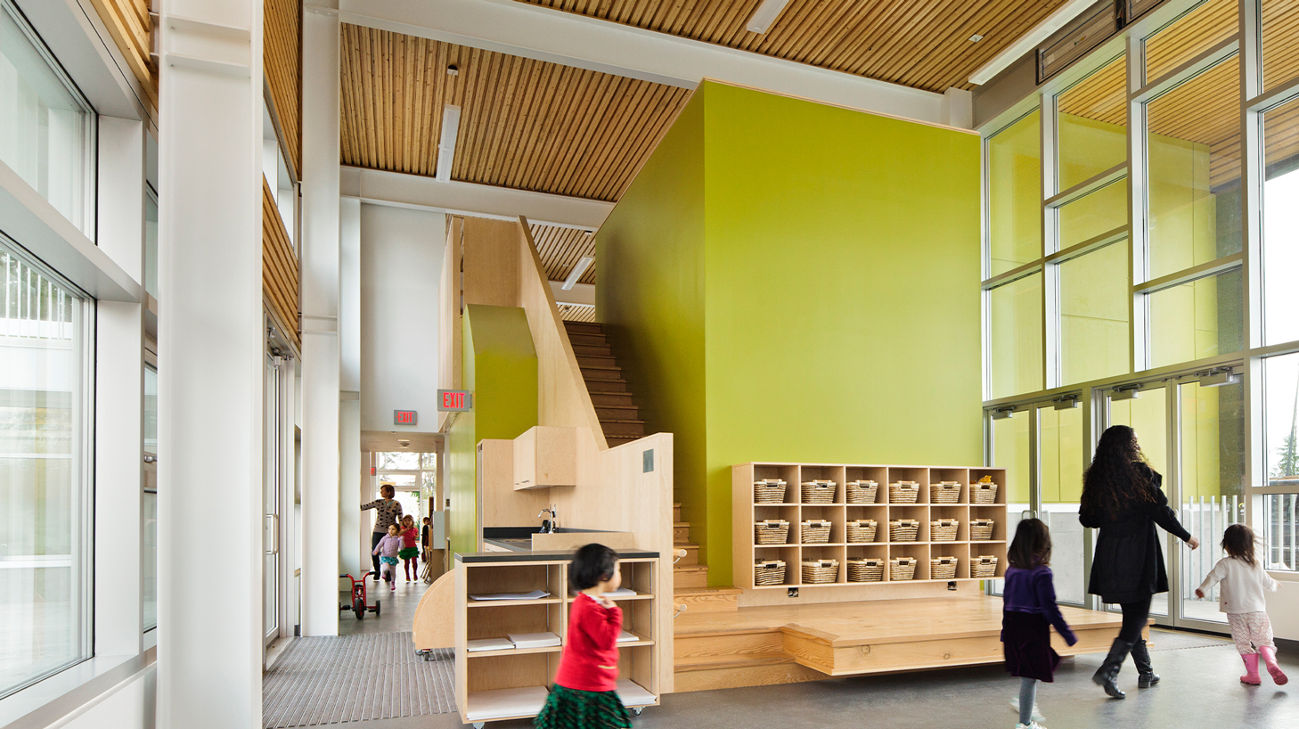 Interior with a family walking past a wooden staircase and neon green wall