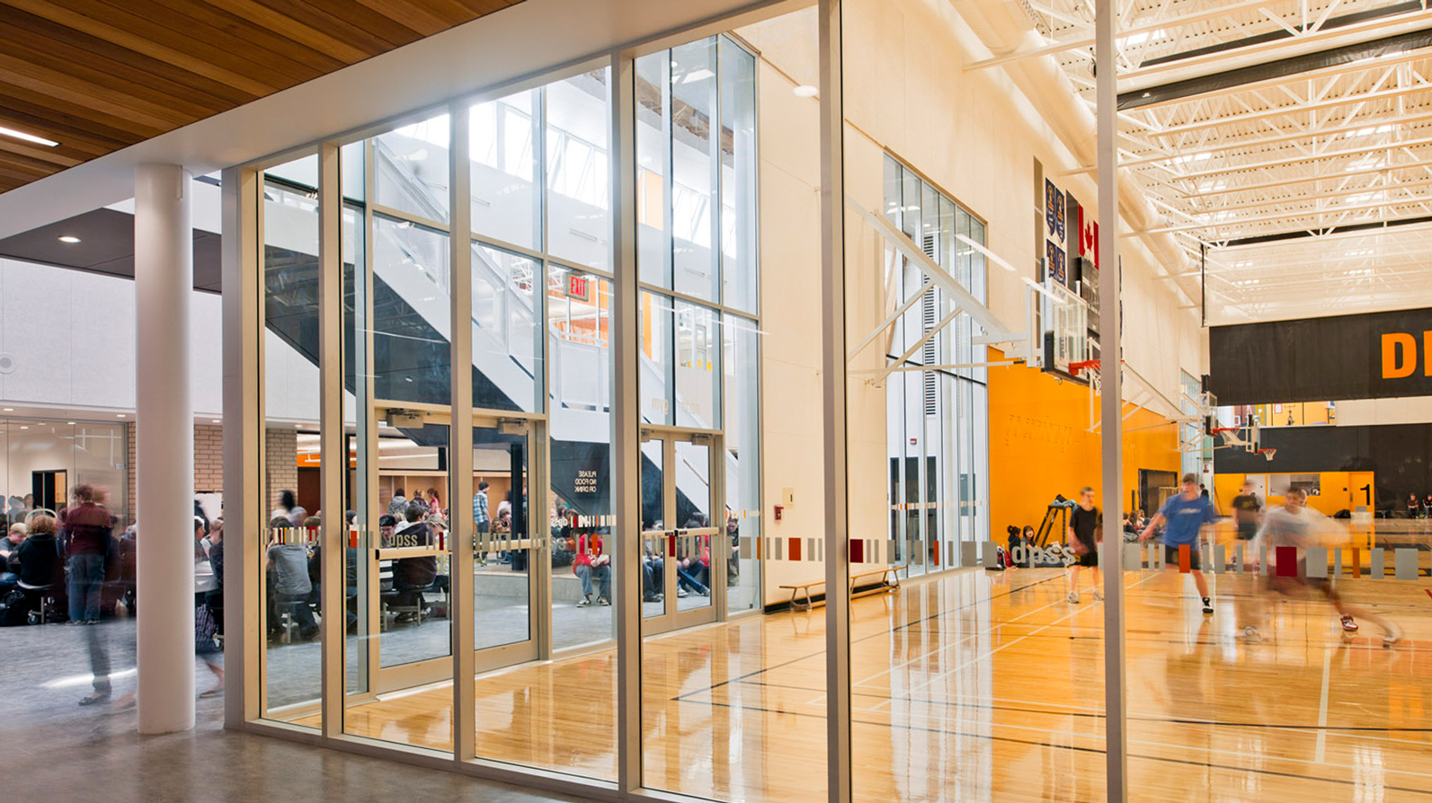 People running in a gym with glass walls