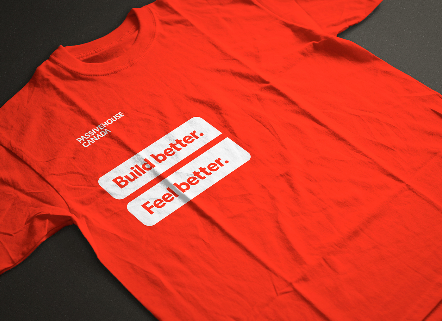 A red T-shirt that has two white rectangles on it that say "Build better." and "Feel better." along with the logo.