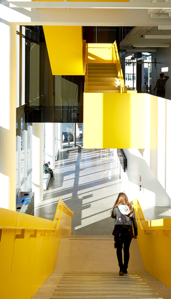 Girl walking down a bright yellow, geometric staircase