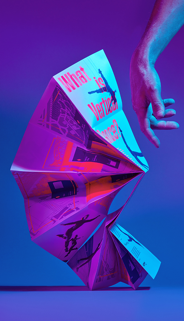 A purple and pink pamphlet spread out like an accordion with a dancer's hand elegantly beside it.