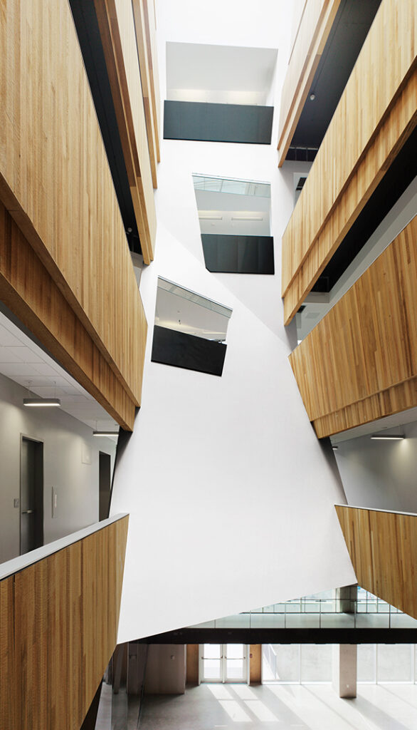 A hallway of wooden balconies leading to a geometric white wall.