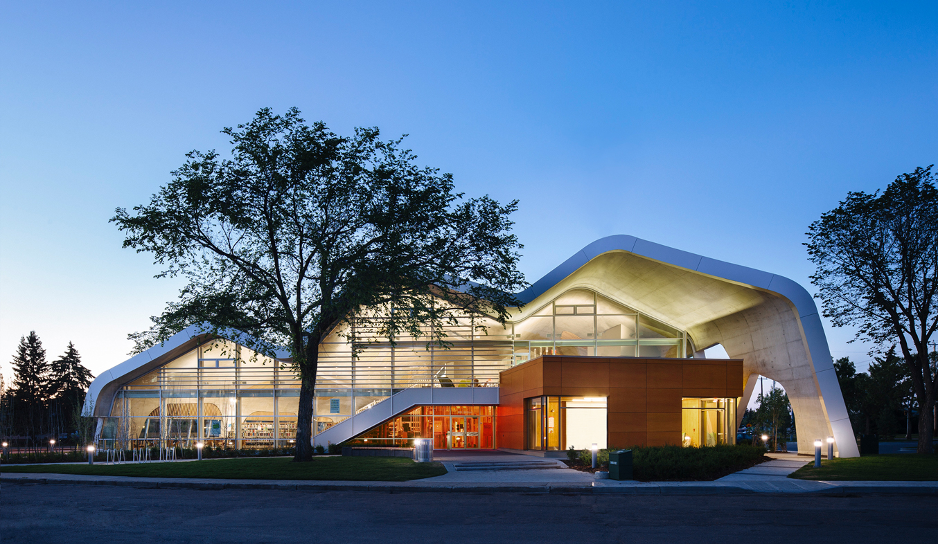 An evening view of Jasper public library, showcasing its organic wavy roof, geometric angles, and windows.