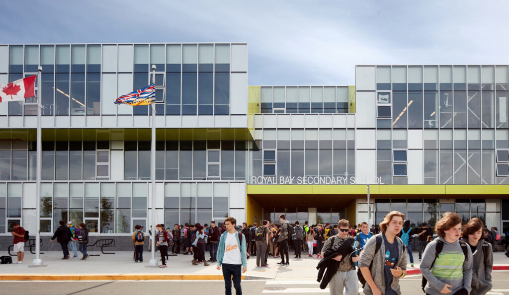 Exterior front view of Royal Bay Secondary School with students walking about and gathered outside.