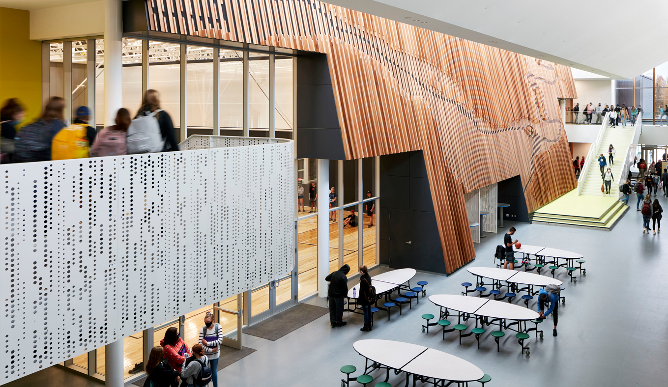 View of the ground floor main space highlighting the perforated metal railing and decorative wood wall art.