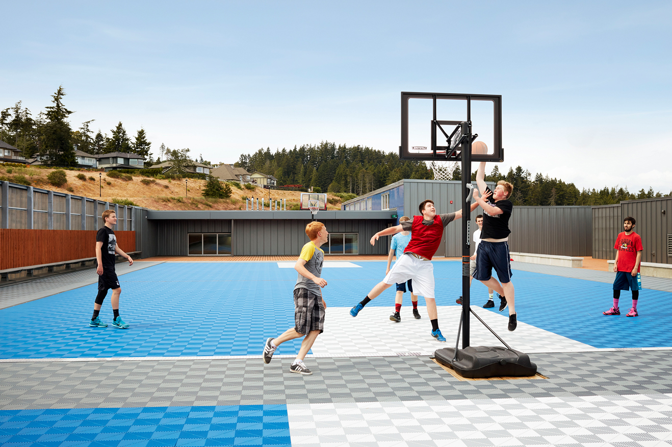 Teenage boys playing basketball on a checkered blue basketball court.