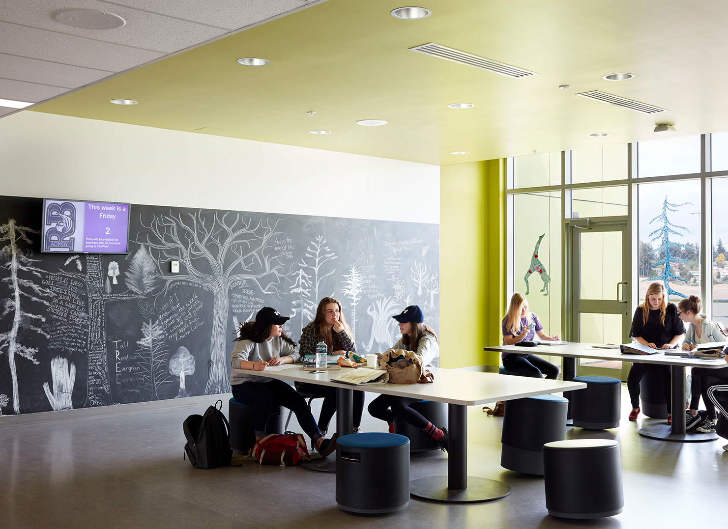 Students sitting at a table in a room with neon green ceiling.