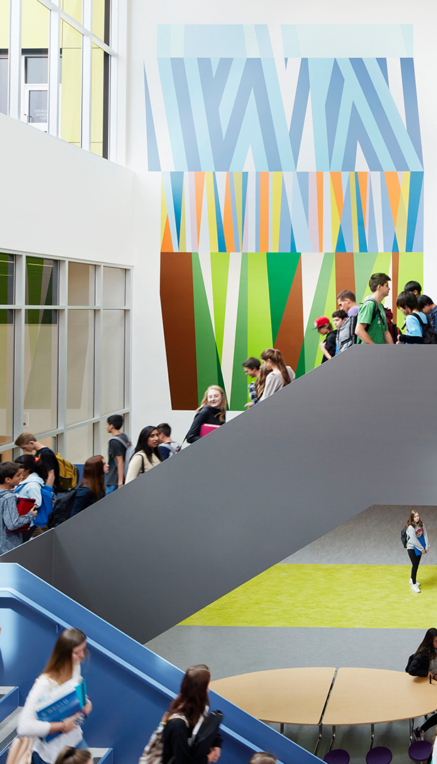 Students walking up colourful staircases with a mural in the background.