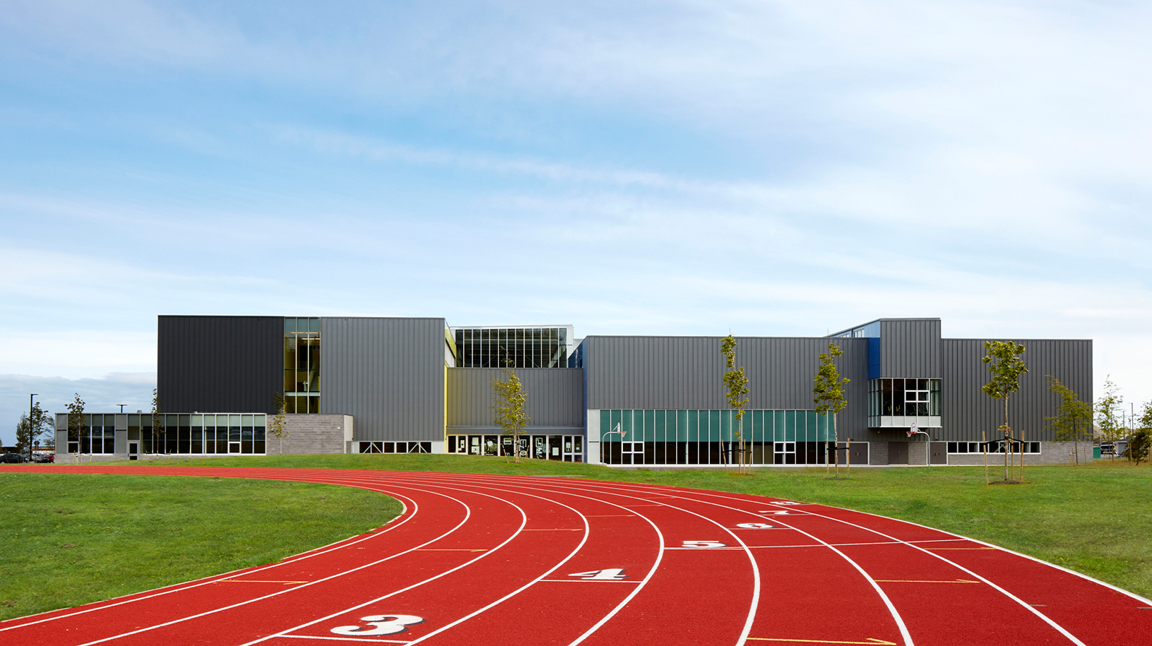 A red running track with the back of the school in the distance.