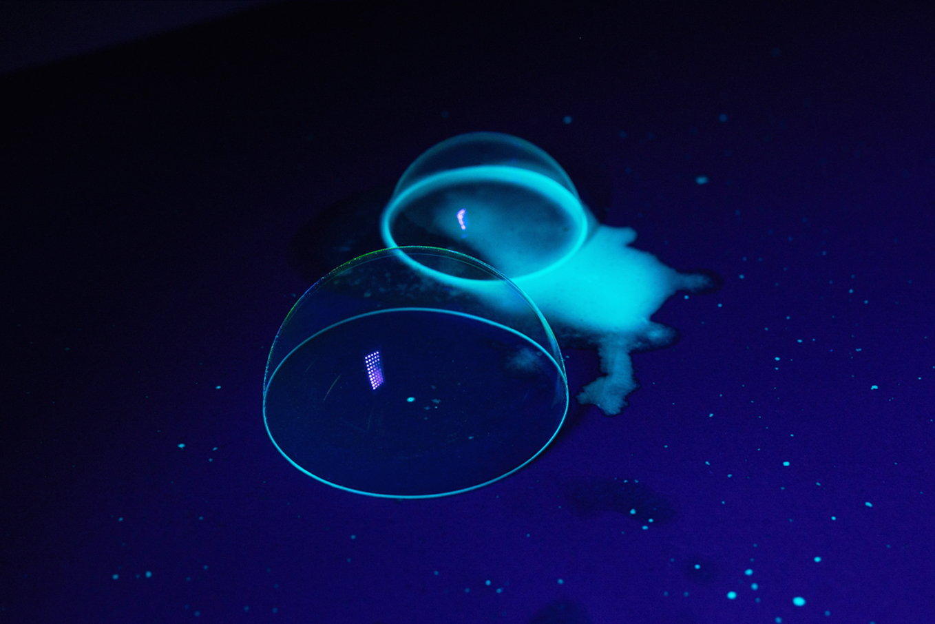 Two glow-in-the-dark soap bubbles under UV light on a table.