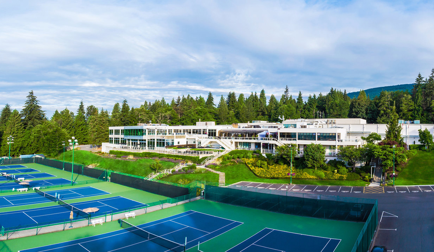 Wide-angle view of Hollyburn Country Club, which has eight tennis courts in front of this long white building.