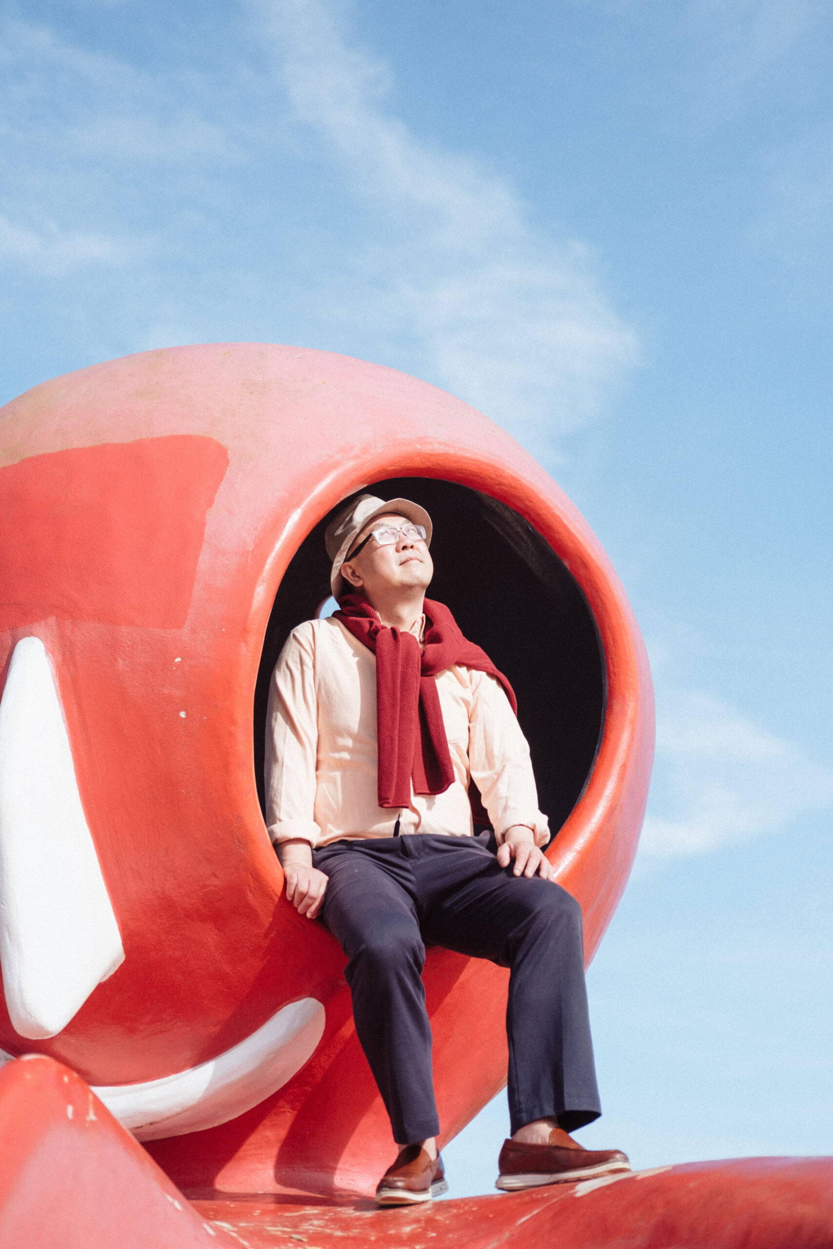 Portrait of Dominic Yu in a red play structure.
