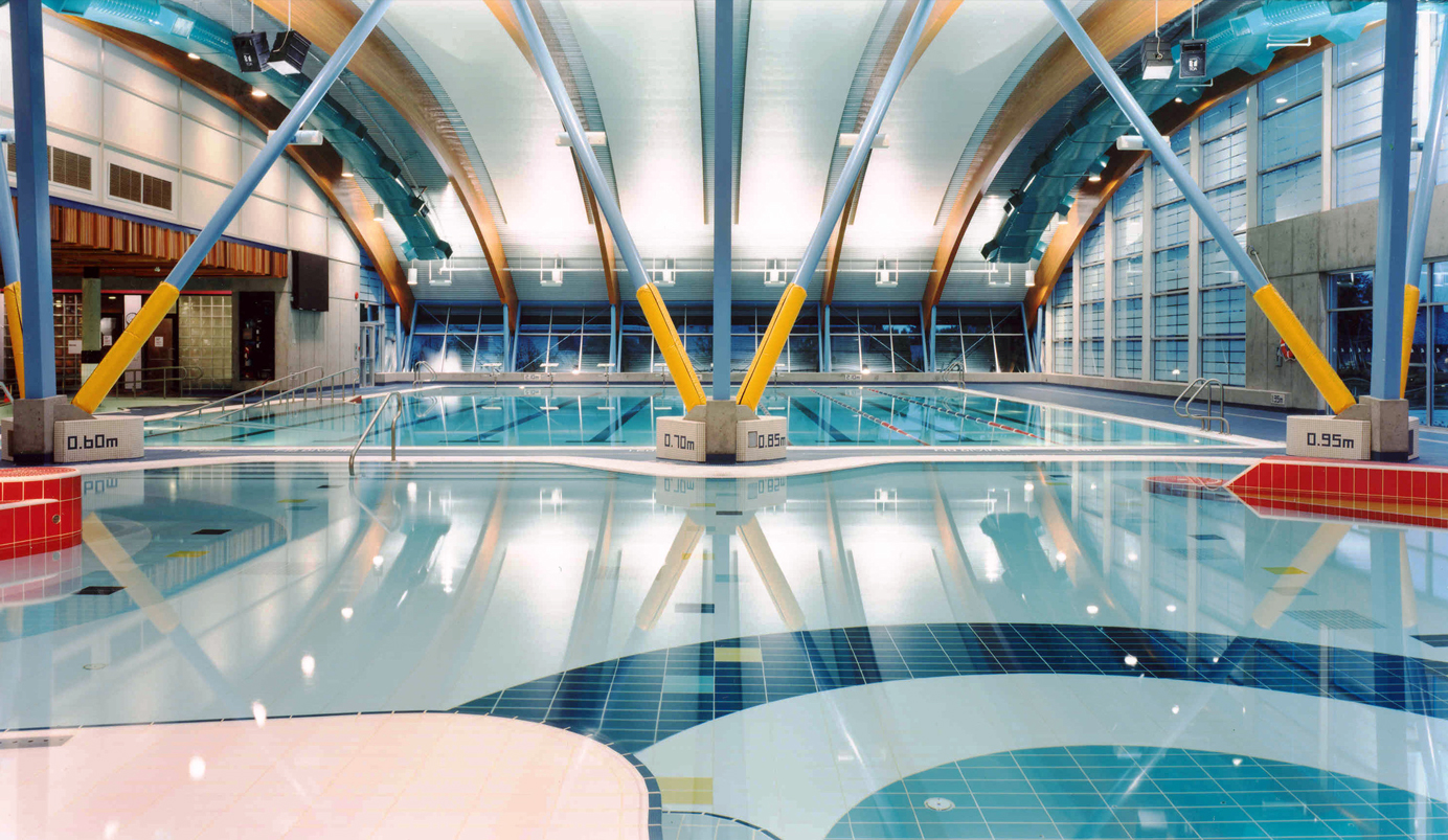 View of the leisure pool and lap pool at Sungod Recreation Centre. The bright primary colour palette bring a sense of energy to the space.