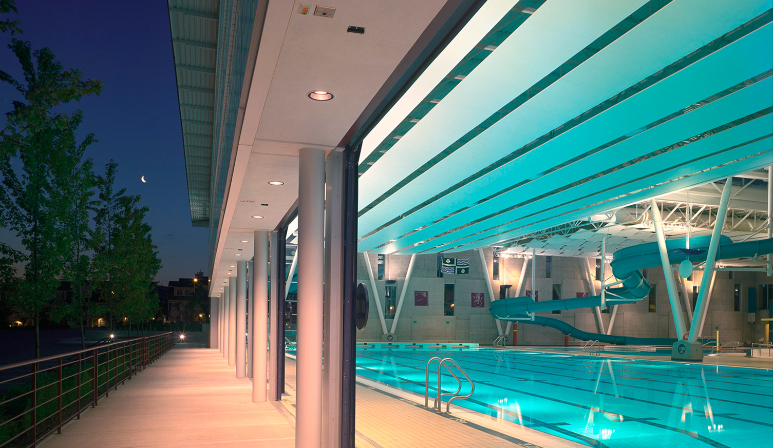 A nighttime view through the open retractable doors into the lap pool at Walnut Grove Community Centre.