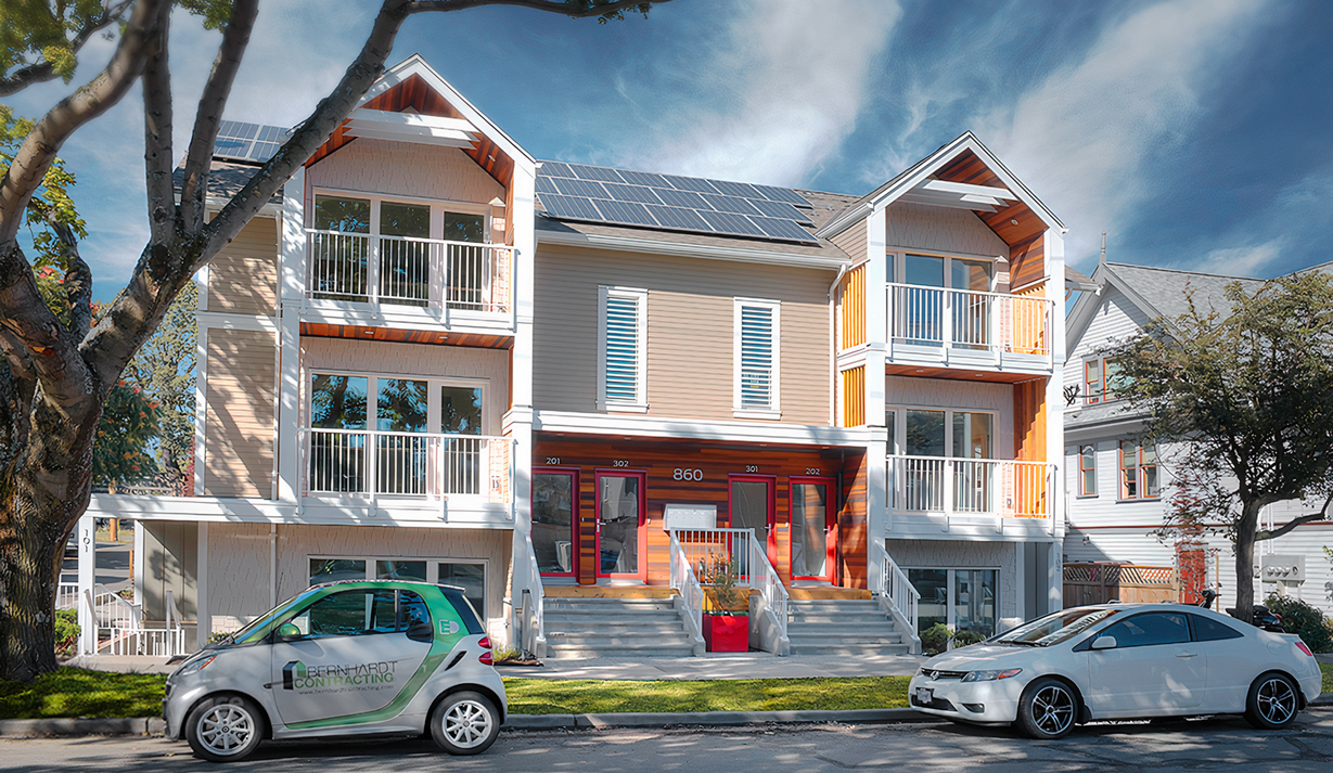 Street view of North Park Passive House. It is a colourful and symmetrical building that showcase solar panels on its roof.