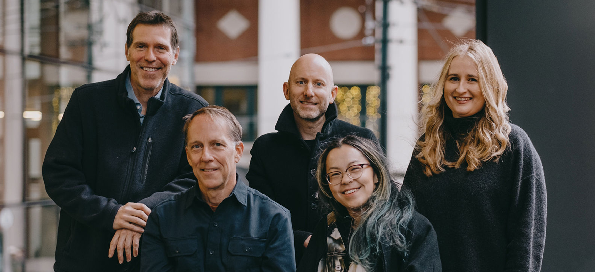 Dan, Michael, Kim, Adam, and Rance in a group photo at Waterfront Station. Dan, Michael, and Kim are standing while Adam and Rance are seated in front of them.