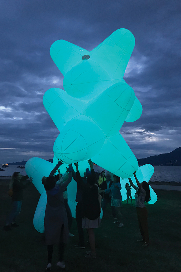 A group of people work together to lift up an inflatable "Jax", from one of the residency's activation events.
