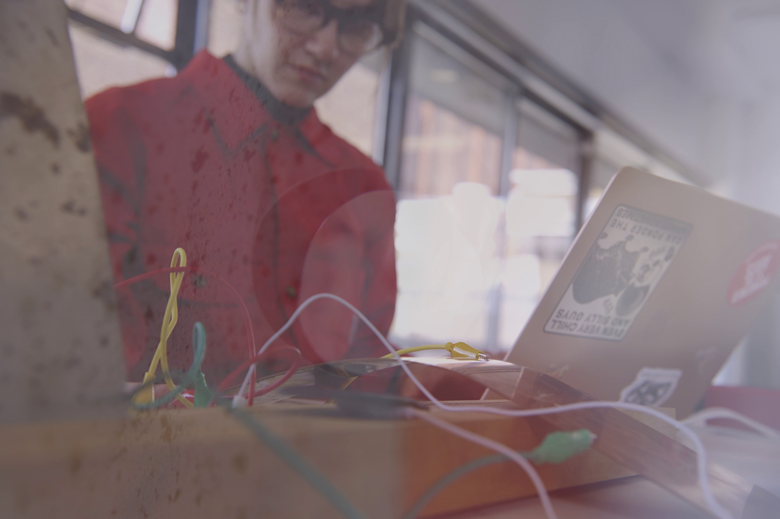 A composite image blending Edie's sound-recording equipment and them working at a laptop in the background.